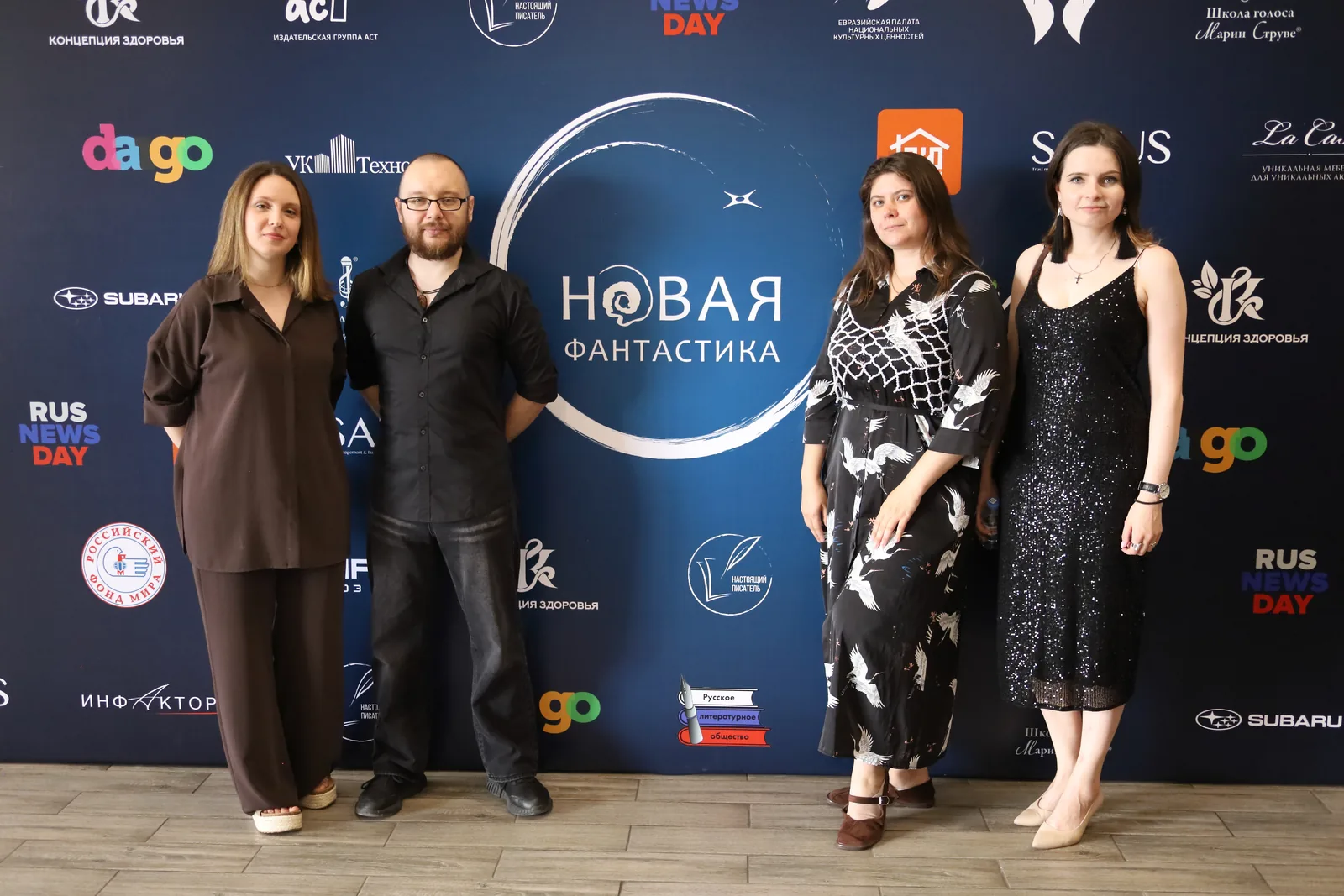 Гости в фотозоне на фоне пресс-волла со знаками партнёров премии